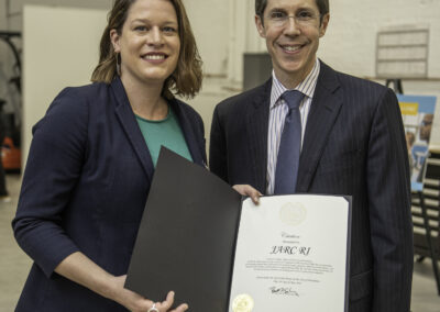 Providence, RI Mayor Brett Smiley presents a citation to Jane Addams Resource Corporation president Regan Brewer in honor of the grand opening of the JARC RI manufacturing training hub.